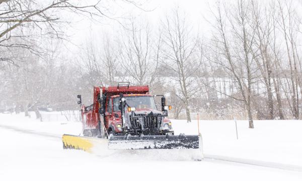 Red snow plow plowing snow off the road