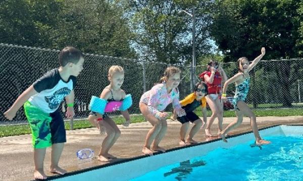 6 kids jumping into an outdoor pool